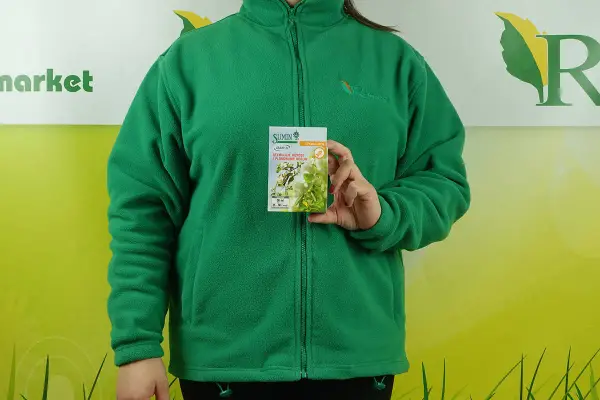 Kobieta w zielonej bluzie trzyma opakowanie stymulatora wzrostu roślin Asahi SL. Na opakowaniu widnieje informacja o dawkowaniu.